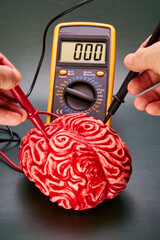 Representation of neuroscience, with a red brain and hands with a voltmeter measuring brain...