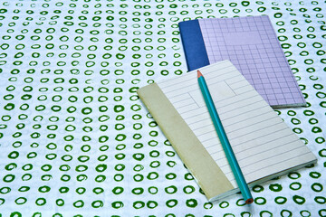Two notebooks with a pencil on top of a green circled surface with copy space. - Powered by Adobe