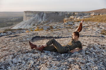 Woman sitting on top of rock with legs up in air enjoying peaceful travel moment by the sea shore