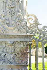 A close-up fragment of the Kucuksu Palace fence: a marble pillar decorated with carvings and a piece of openwork lattice. An example of Ottoman Baroque in Istanbul, Turkey.