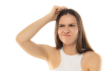 Portrait of a young teenage girl nervously thinking and scratching her head with her finger on a...