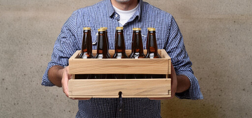 Man carries wooden box full of unmarked drinks bottles.
