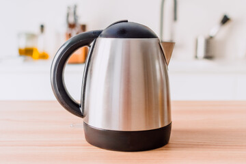 A silver tea kettle sits on a wooden table