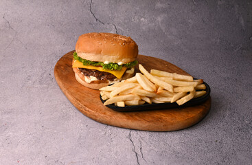 Beef patty burger with French fries on wooden plate