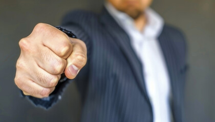 A man in a suit pointing hist fist