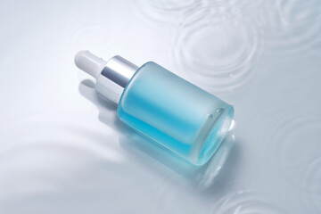 Bottles of cosmetics with a dropper in water on a blue background.