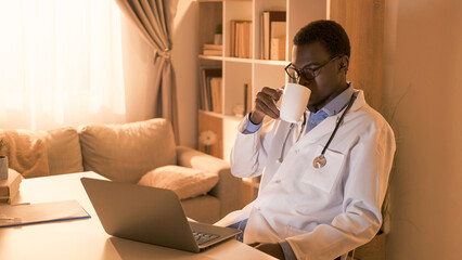 Doctor break. Medic lifestyle. Relaxed serious male physician in white coat with mug watching...