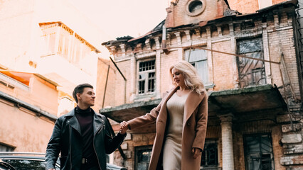 Old city walk. Urban date. Romantic weekend. Carefree couple in love holding hands enjoying strolling together outside on street with abandoned house.