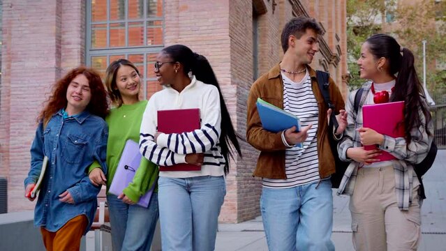 Multiracial group of students walking around college campus laughing outdoors Young community of people having fun together.