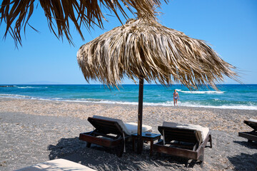 Paralia Karterados, wild volcanic sand beach with thatched umbrellas. Greek islands, Santorini,...