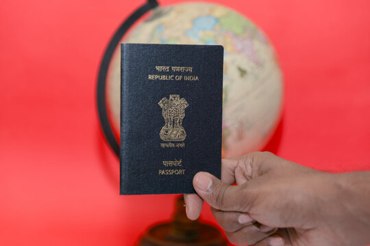 Man hand holding Indian passport and globe on red background Travel concept