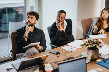 A diverse group of business professionals is deeply engaged in a strategic discussion, analyzing...