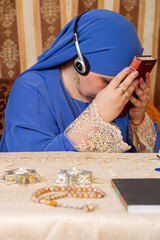 A Jewish woman at a table reads the Torah and conducts an online lesson
