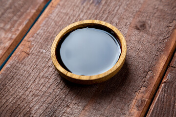 soy sauce in a wooden plate on a board on the table