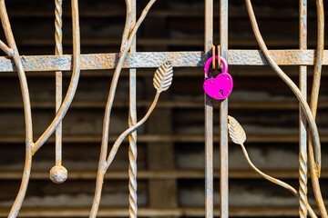 a heart-shaped padlock hanging on a metal gate.