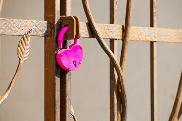 a heart-shaped padlock hanging on a metal gate.