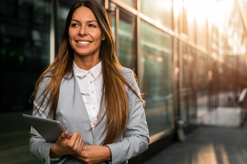 Stylish young businesswoman with digital tablet in downtown financial district in the city.