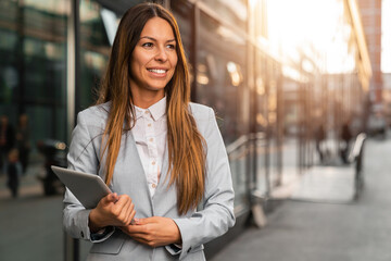 Portrait of a confident businesswoman standing outside with a digital tablet.