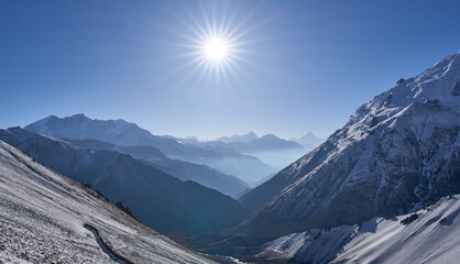 Sunrise seen on the way from Tilicho Base Camp to Tilicho Lake. Most popular hiking trail in Annapurna Conservation Area. Mountain chains and Manaslu summit in background. Rays radiating from the sun.