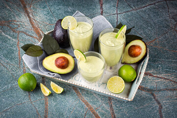 Traditional fruit smoothie with avocado, tropical juices and yoghurt served as close-up on a wooden design tray