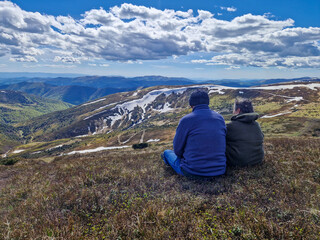 Fototapeta premium two elderly people are sitting and admiring the mountain landscape.