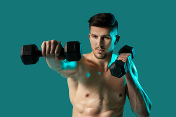 A shirtless man is shown standing on a green background while holding dumbbells in each hand. He...