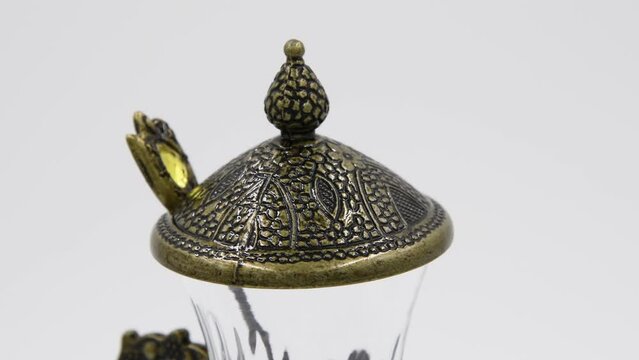 Close-up side view of empty armudu (armuda, bogmaly) - traditional metal and glass tea or coffee cup with small spoon from Turkey or Azerbaijan. Souvenir from travel turning on gray background.