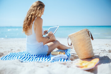 relaxed woman on ocean shore using applications on tablet PC