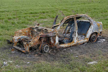 Burned down car in the field. Full destroyed vehicle.