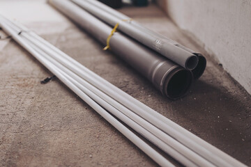 Gray PVC sewer pipes on a cement floor background. Plumbing tool pipes in renovating apartment...