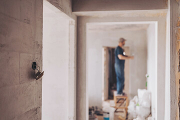 the wall in a building under construction with a worker in the background. renovating apartment...