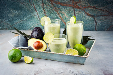 Traditional fruit smoothie with avocado, tropical juices and yoghurt served as close-up on a wooden...