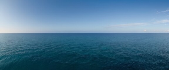 Wide panoramic view of the open ocean under clear blue skies, symbolizing freedom and the vastness of nature, perfect for backgrounds or conceptual use.