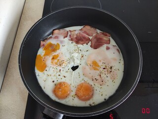 Scrambled eggs with cheese, bacon and spices fried in a frying pan