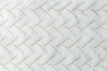 A white knit blanket with a zigzag pattern. Repetitive abstract pattern.