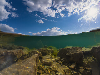 Underwater photo at the Rummu quarry, clear water, rocky bottom and cloudy sky.