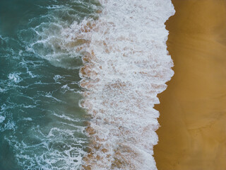 Photo background texture, view from a drone of the waves on the sandy beach of Nazaré.