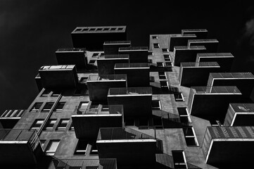 View from underneath of a residential building with balconies in black and white