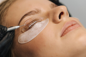 Close-up of eyelash care treatment procedures. Beautiful female, blond hair model have eyelashes...