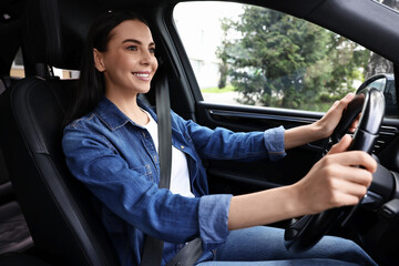 Woman with seatbelt holding steering wheel while driving her car