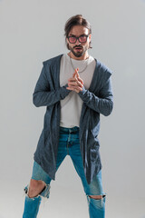 bearded casual man in hoodie with sunglasses holding hands together