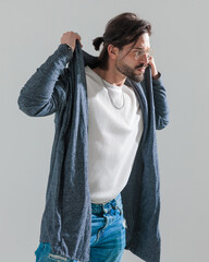 casual fashion man with long hair adjusting hoodie and looking to side