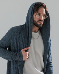 sexy bearded man with golden frame eyeglasses adjusting hoodie