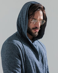 side view of casual young man with glasses and hoodie looking to side