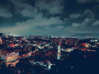 Panorama urbano de noche, iluminación de bombillos de calles y viviendas. Barrio o comunidad popular de la ciudad de Caracas en Venezuela