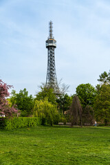 Obraz premium Prague, Czech Republic - April 14, 2023: Petrin observation tower in Prague located in a park among trees on a hill above the city.