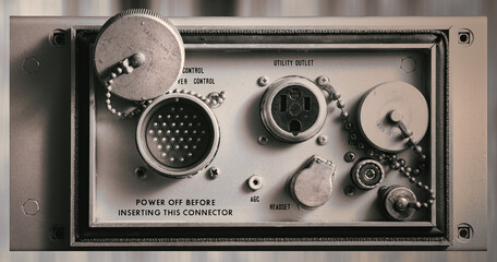 Old electronic device’s front panel with control knobs and switches, a utility outlet, and a...