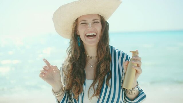 smiling modern 40 years old woman on the seacoast with sunscreen.