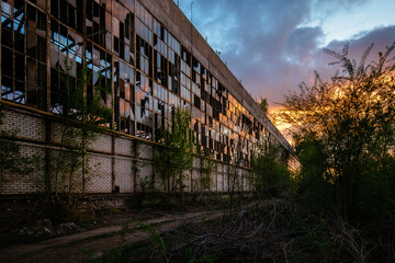 Fototapeta premium Old abandoned industrial building at sunset