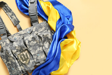 Unloading vest with badge of Ukrainian army and Ukraine flag on beige background